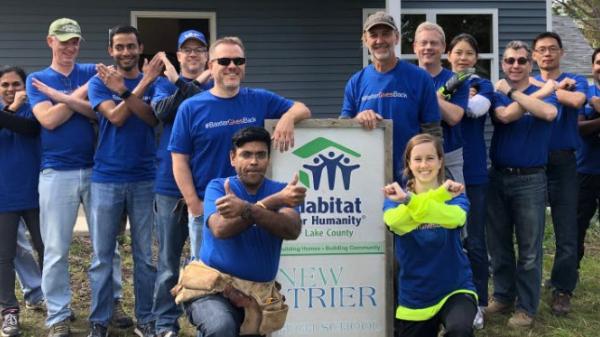 Baxter employees pose in front of a Habitat for Humanity Home