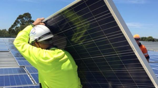 Employee moves a solar panel on a rooftop